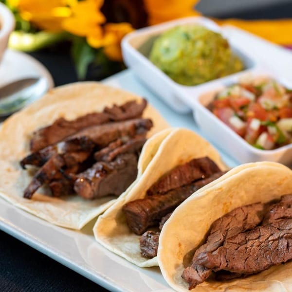 Three steak tacos with guacamole and salsa on a white plate at Chitos Authentic Mexican Restaurant.
