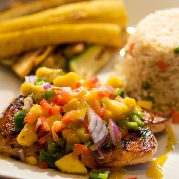 Grilled chicken with mango salsa, rice, and plantains on a white plate at Chitos Authentic Mexican Restaurant.