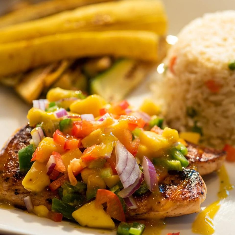 Grilled chicken with mango salsa, rice, and plantains on a white plate at Chitos Authentic Mexican Restaurant.