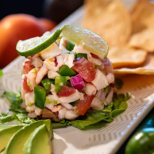 Chitos Mexican ceviche with shrimp, red onion, tomato, and green pepper, garnished with lime and avocado.