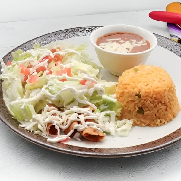 Chitos Mexican meal with taquitos, shredded lettuce, tomatoes, sour cream, rice, and refried beans.