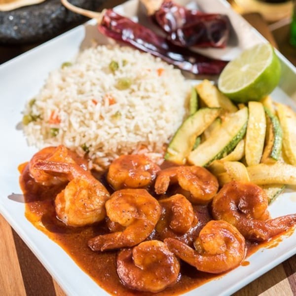 Chitos Mexican shrimp dish with rice, zucchini, and a lime wedge on a white plate.